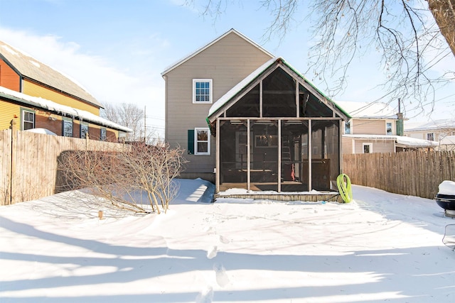 snow covered property featuring fence and a sunroom