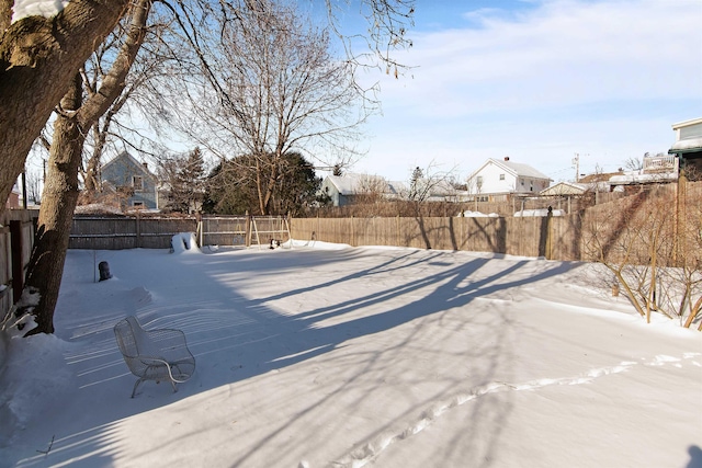 snowy yard featuring a fenced backyard