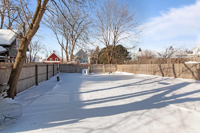 yard layered in snow featuring a fenced backyard