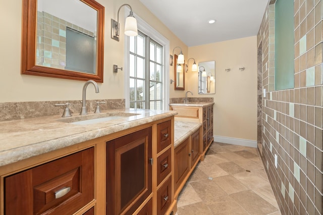 full bathroom featuring two vanities, baseboards, and a sink