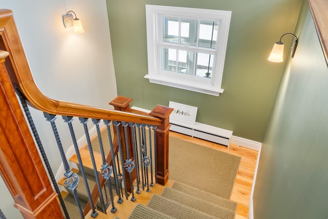 stairs with wood finished floors, baseboards, and a baseboard radiator