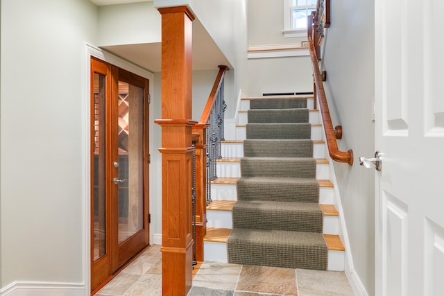 stairway featuring stone finish floor and baseboards