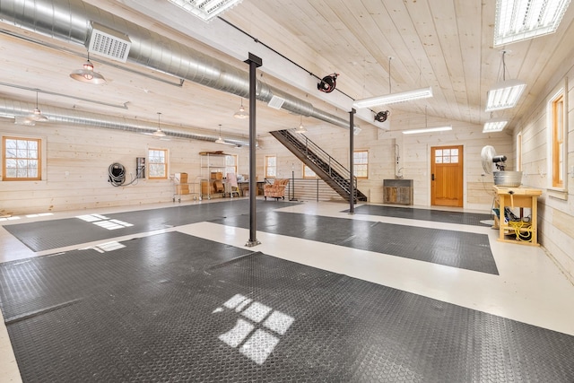 miscellaneous room featuring visible vents, wood walls, concrete flooring, wooden ceiling, and a wood stove