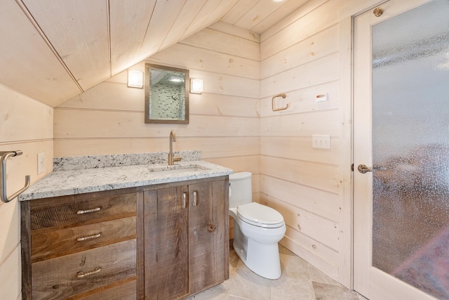 bathroom with wooden walls, toilet, vanity, and lofted ceiling