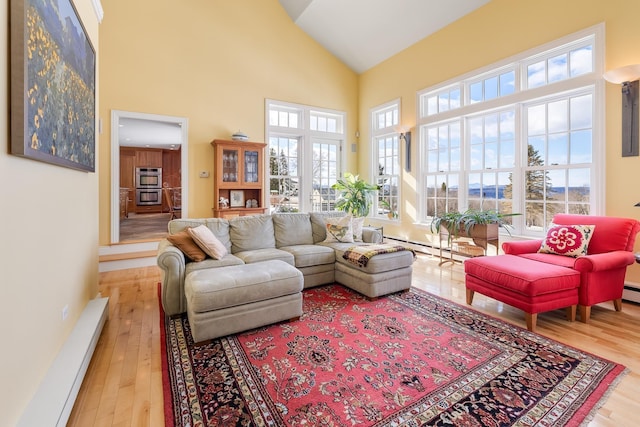 living room featuring baseboard heating, high vaulted ceiling, and wood finished floors