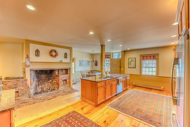 kitchen featuring light wood-style flooring, appliances with stainless steel finishes, a fireplace, and a baseboard heating unit