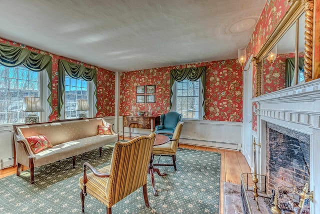 living area featuring hardwood / wood-style floors, a high end fireplace, wainscoting, wallpapered walls, and baseboard heating