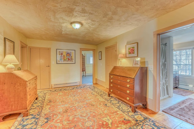 corridor with baseboards, a textured ceiling, light wood-style floors, and a baseboard radiator