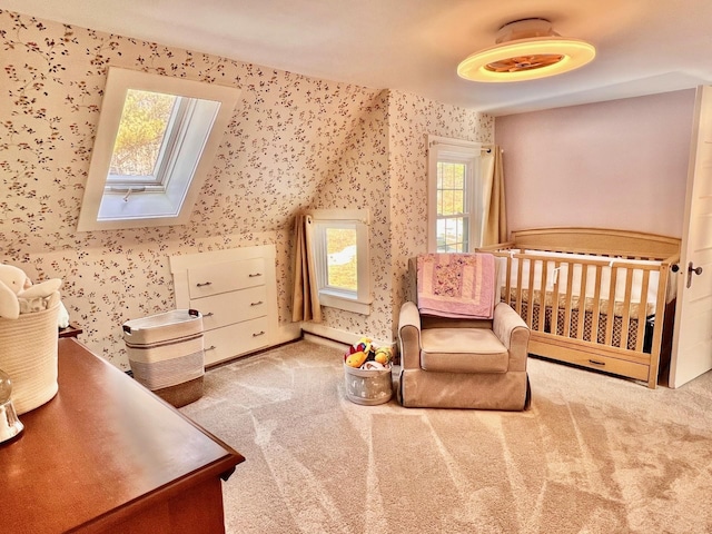 bedroom featuring a crib, carpet floors, a skylight, and wallpapered walls