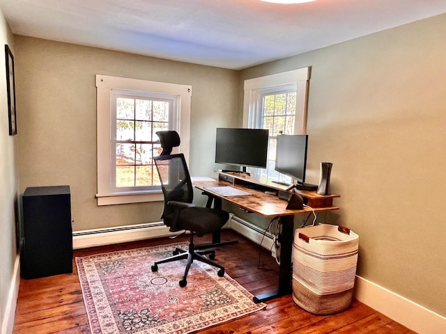 home office featuring a baseboard heating unit, baseboards, and wood-type flooring