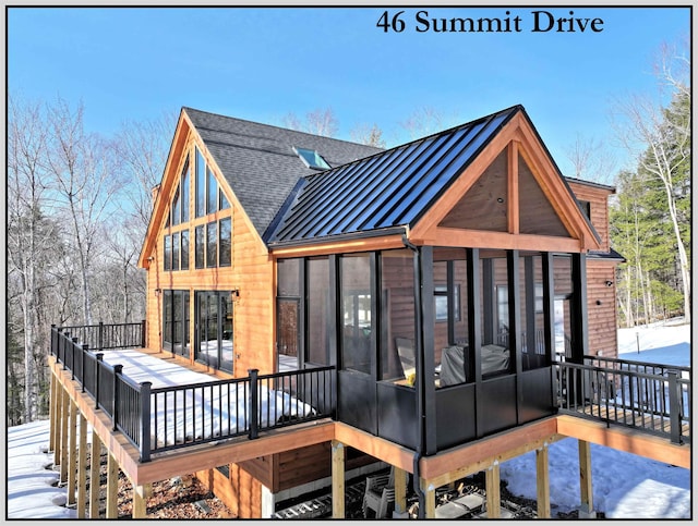 rear view of house featuring a shingled roof, metal roof, a standing seam roof, and a sunroom