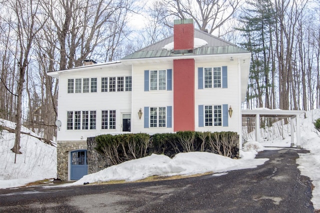 view of front of home featuring stone siding, a chimney, and metal roof