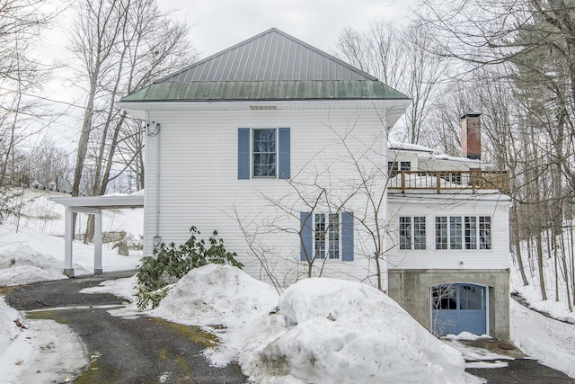 view of snow covered exterior with metal roof and a balcony