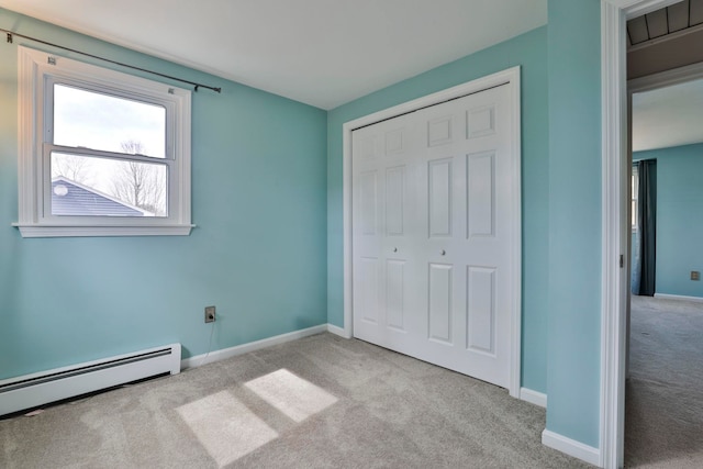 unfurnished bedroom with a baseboard heating unit, baseboards, a closet, and carpet flooring