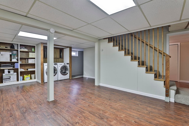 below grade area with stairway, wood finished floors, independent washer and dryer, and a paneled ceiling