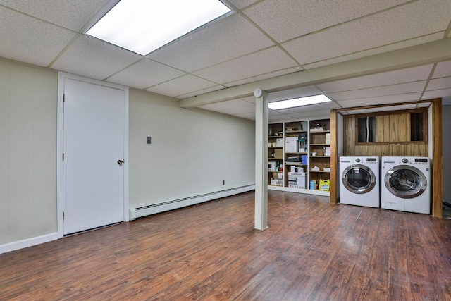 clothes washing area with wood finished floors, washing machine and dryer, and a baseboard radiator