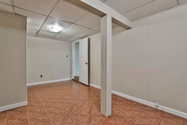 finished basement featuring baseboards and a drop ceiling