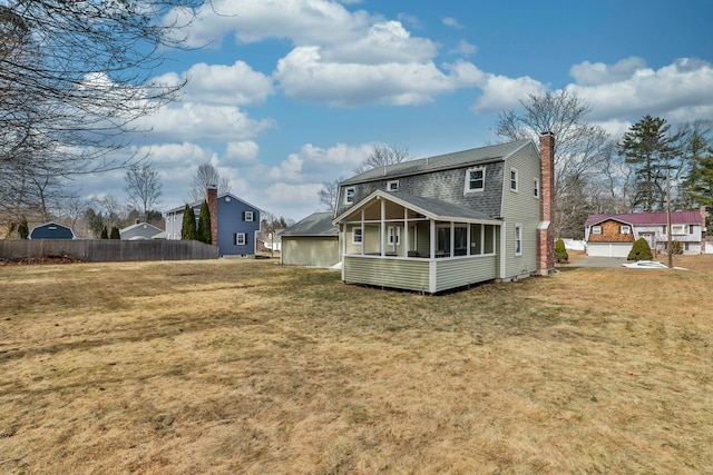 back of house with a chimney, a sunroom, a yard, and fence