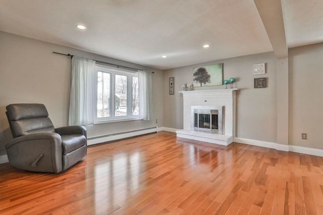 unfurnished room with light wood-style flooring, a brick fireplace, baseboards, and a baseboard radiator