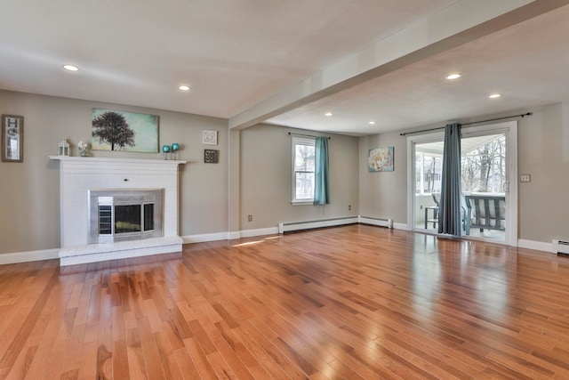 unfurnished living room featuring a baseboard radiator, baseboards, light wood-style flooring, and a fireplace