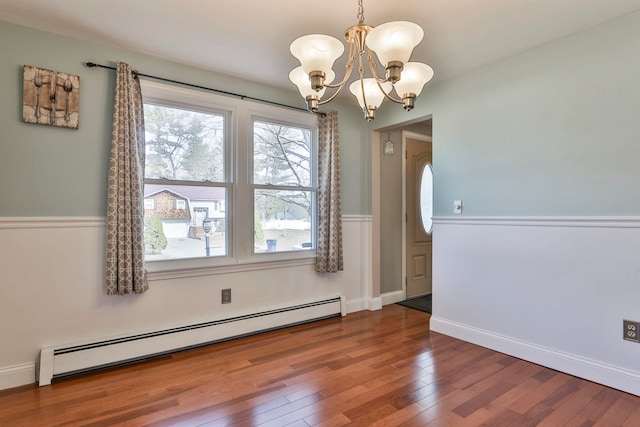 unfurnished dining area featuring a notable chandelier, wood finished floors, baseboards, and a baseboard radiator