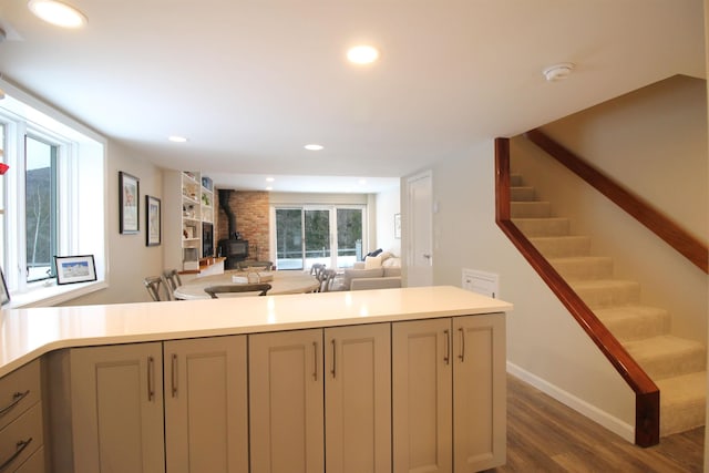 kitchen with dark wood finished floors, a wood stove, recessed lighting, gray cabinets, and light countertops