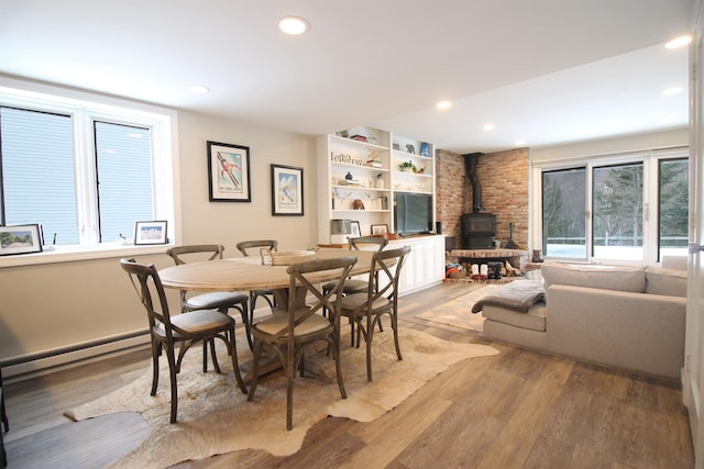 dining space with a baseboard heating unit, a wood stove, recessed lighting, and light wood-type flooring