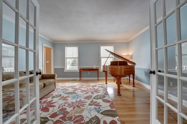 living area featuring baseboards, french doors, light wood-type flooring, and ornamental molding