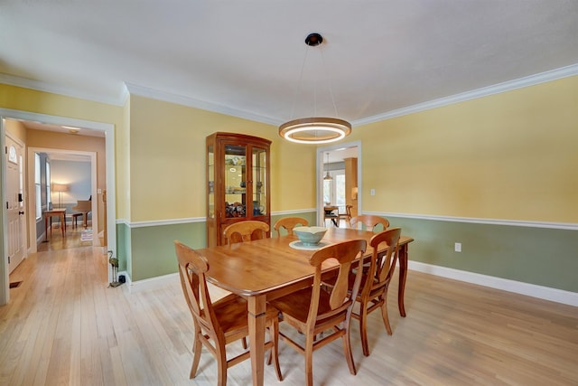 dining area with light wood-style floors, baseboards, and ornamental molding