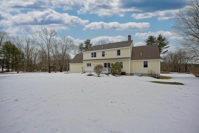 snow covered back of property with a chimney