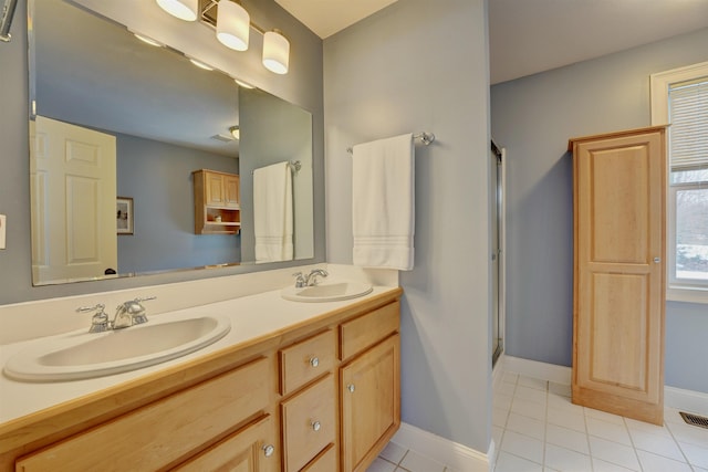 full bathroom with double vanity, an enclosed shower, baseboards, and a sink