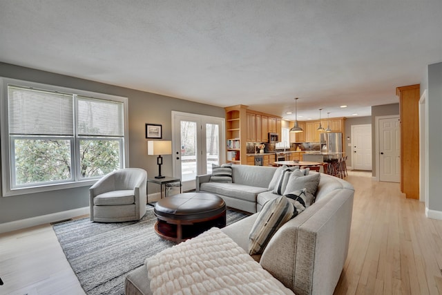 living room featuring light wood finished floors, visible vents, recessed lighting, and baseboards