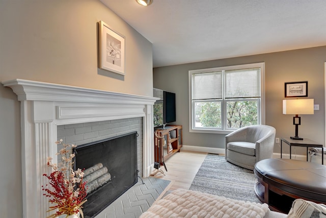 living room with light wood-style floors, a fireplace, and baseboards