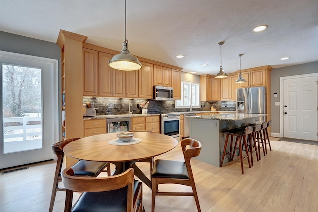 kitchen featuring wine cooler, a kitchen island, appliances with stainless steel finishes, and light brown cabinets