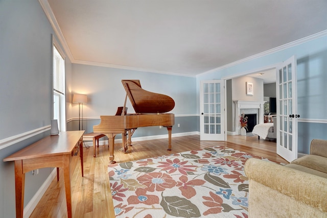 living area with wood finished floors, french doors, a fireplace, crown molding, and baseboards