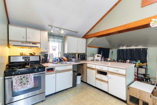 kitchen featuring under cabinet range hood, light floors, vaulted ceiling, stainless steel gas stove, and a sink