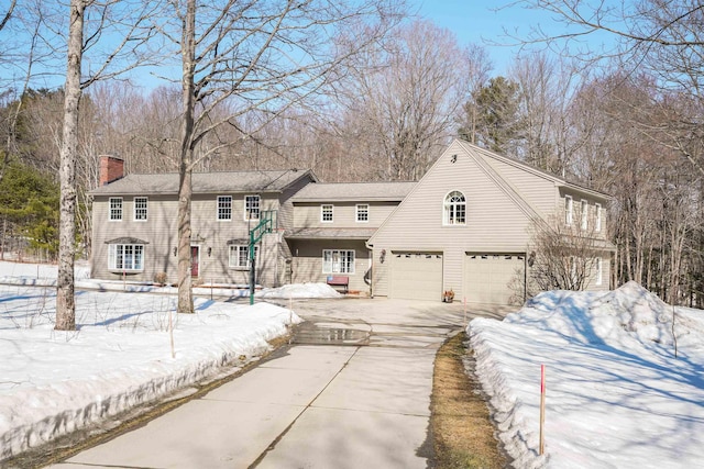 view of front of home featuring an attached garage, driveway, and a chimney