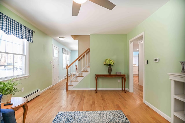 foyer entrance with wood finished floors, stairs, baseboards, and a baseboard radiator