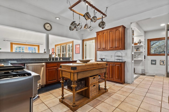 kitchen with light tile patterned floors, brown cabinets, stainless steel appliances, and a sink