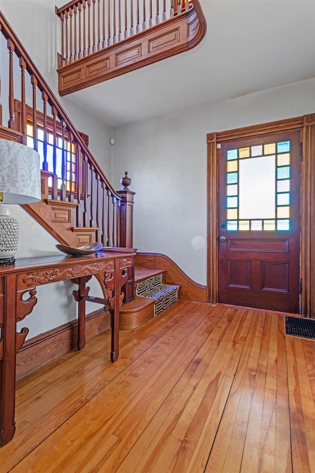 foyer featuring light wood-type flooring, stairway, and visible vents