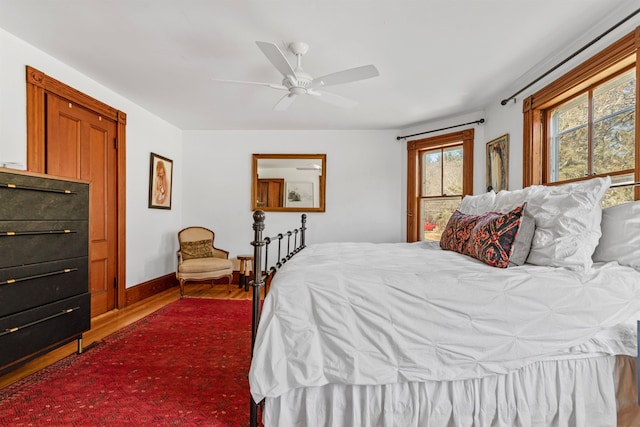 bedroom featuring ceiling fan, baseboards, and wood finished floors