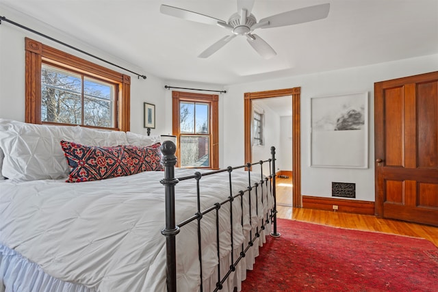 bedroom with visible vents, baseboards, wood finished floors, and a ceiling fan