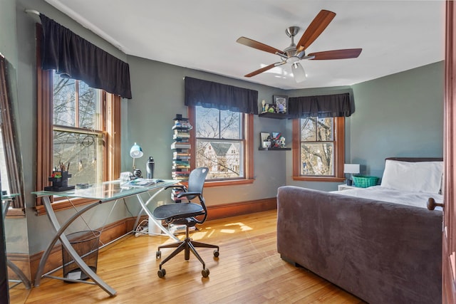 bedroom featuring baseboards, multiple windows, and wood finished floors