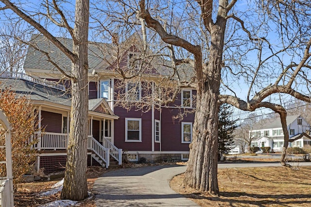 view of front of home with stairway, roof with shingles, covered porch, and driveway