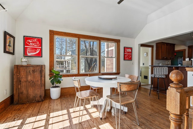 dining space with baseboards, wood finished floors, and vaulted ceiling