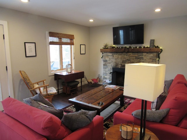 living area with a stone fireplace, recessed lighting, and wood finished floors