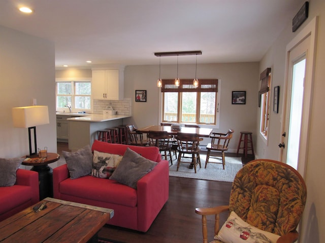 living area with dark wood-type flooring, recessed lighting, and a healthy amount of sunlight