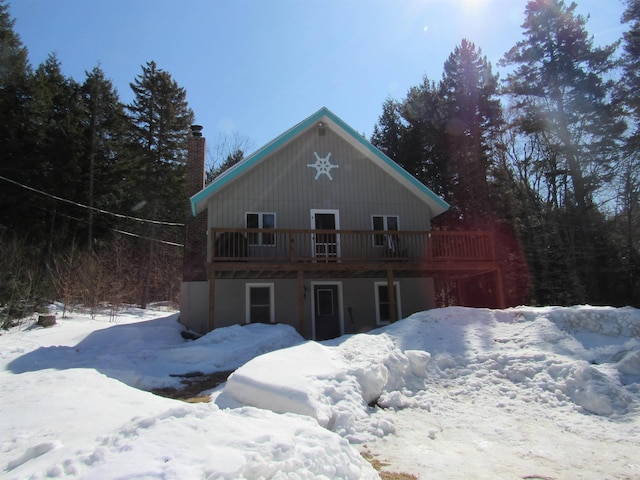 snow covered back of property featuring a deck