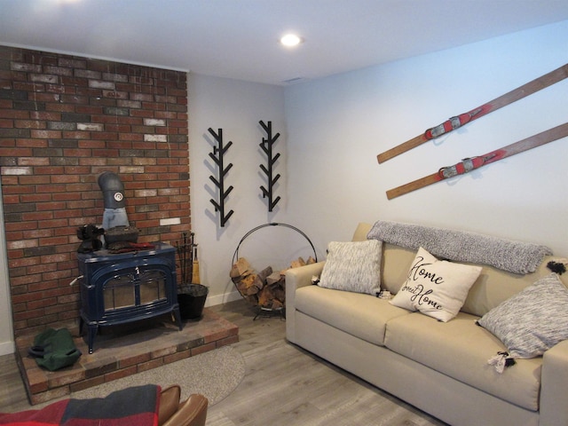 living room featuring recessed lighting, a wood stove, baseboards, and wood finished floors