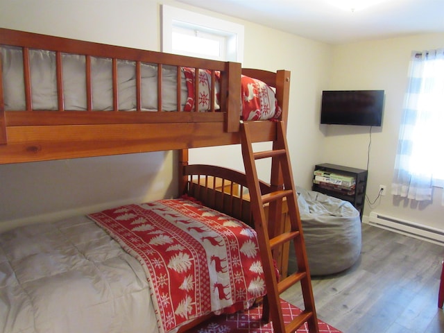 bedroom with wood finished floors and baseboard heating